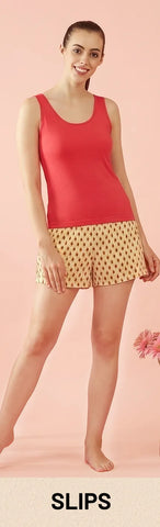 Woman wearing red camisole slip with printed shorts in soft pastel background